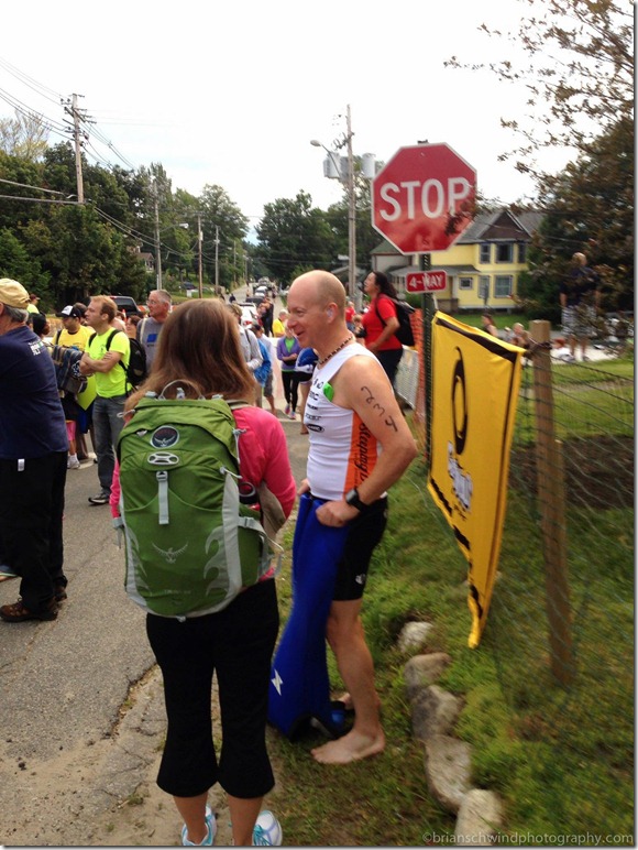 Putting on wetsuit before the swim. Denise with backpack watching me